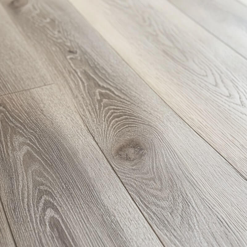 Närbild av ett ljusgrått trä-look laminatgolv med naturliga ådringsmönster